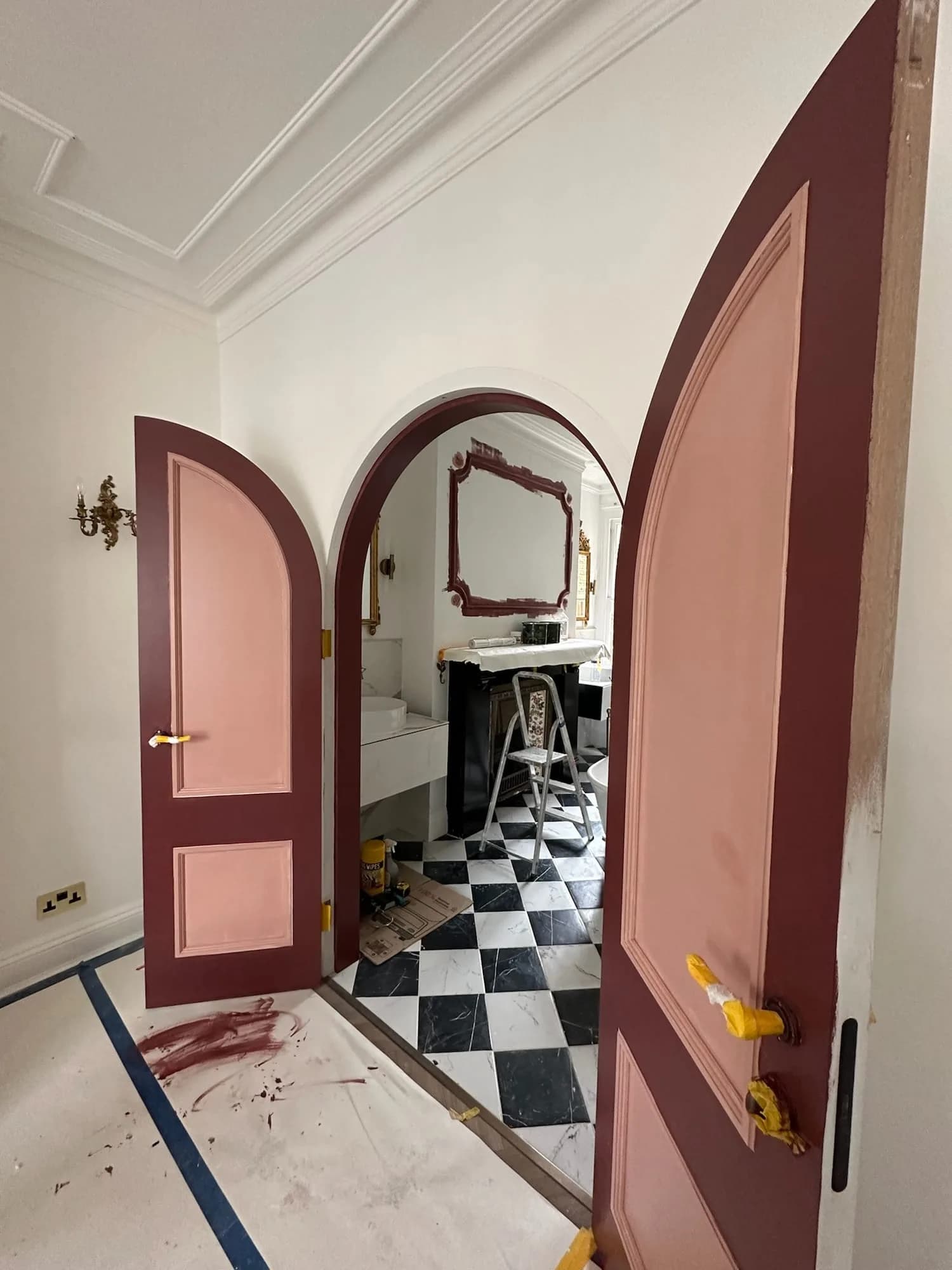 Belgravia: arched raspberry-pink doors opening to a cloakroom with a chequerboard floor