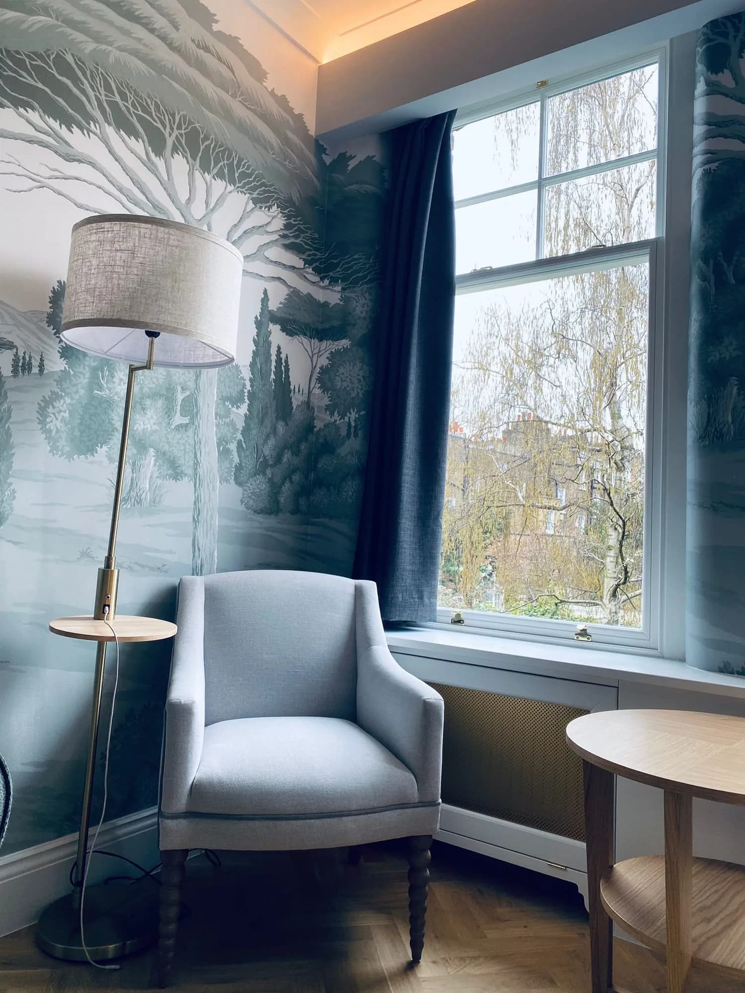 Chelsea I: armchair beside a sash window against hand-painted landscape wall panels