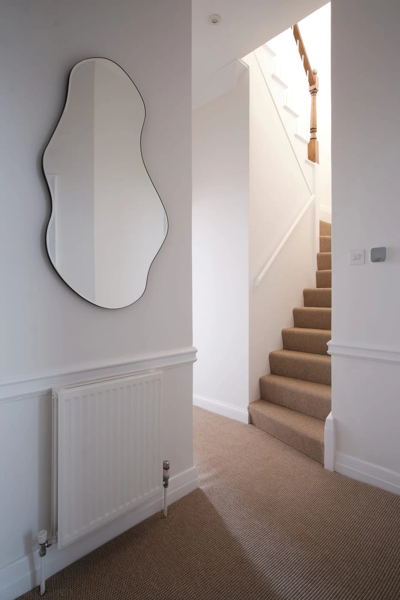 Chelsea II: landing with a curved frameless mirror beside the carpeted stair