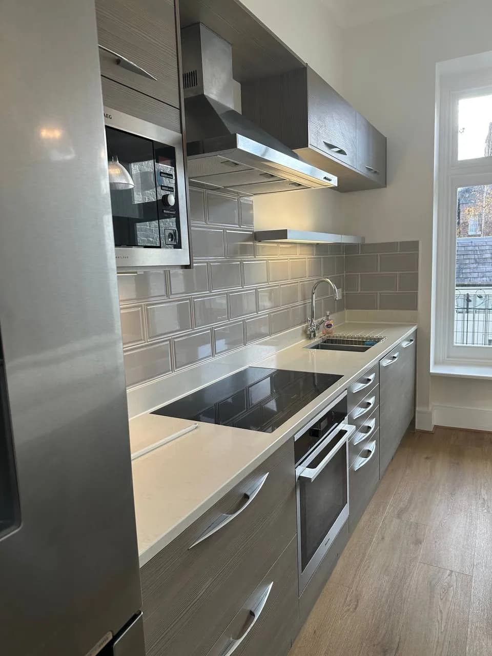 Chelsea II: galley kitchen with grey timber-effect units and a stainless extractor