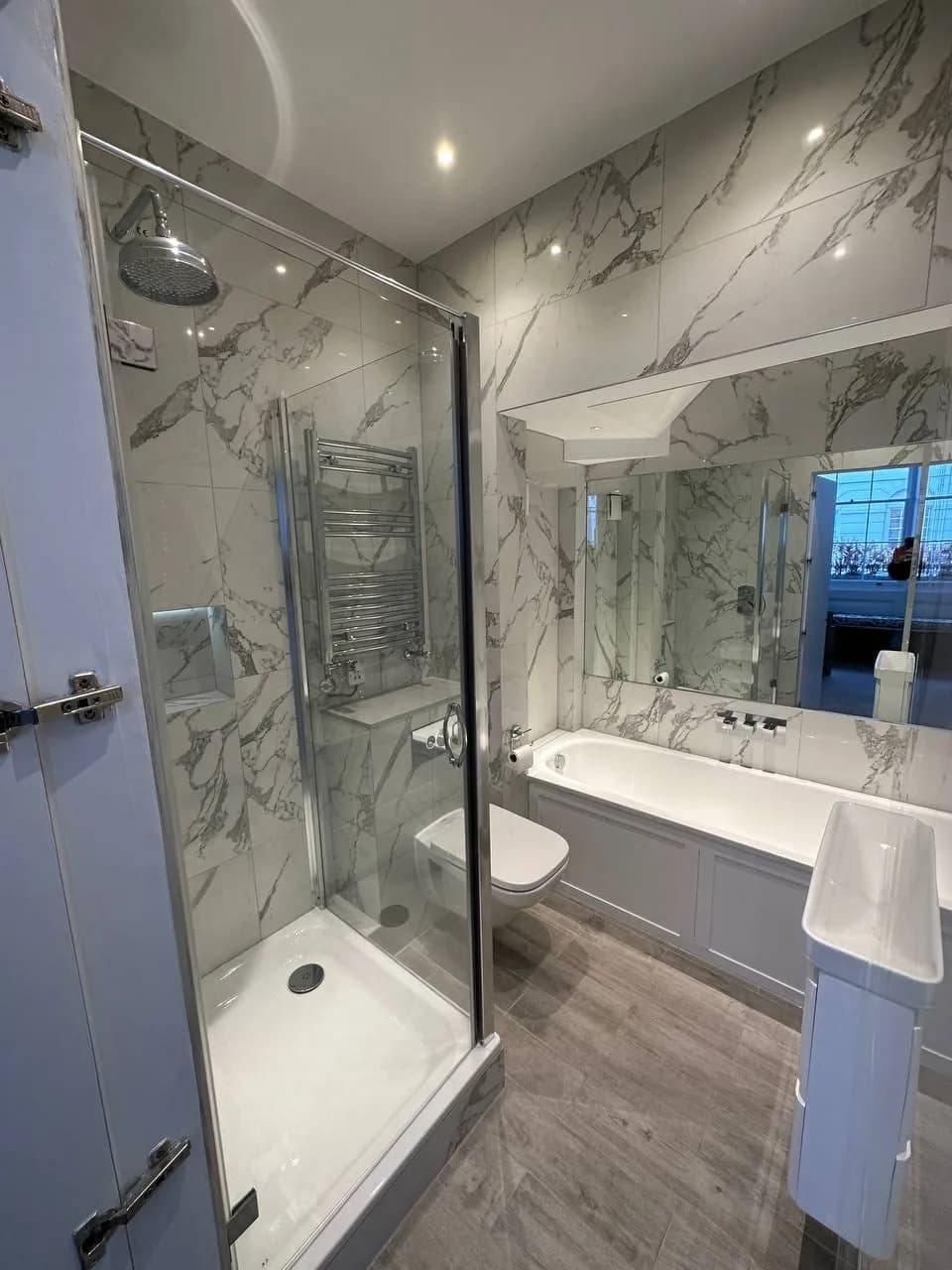 Chelsea II: walk-in shower and bath in marble-effect tiling with a heated towel rail