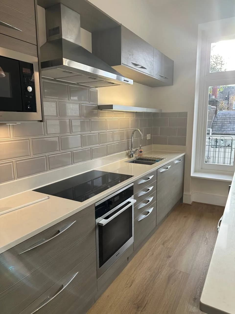 Chelsea II: kitchen run with an induction hob, integrated oven and metro-tiled splashback