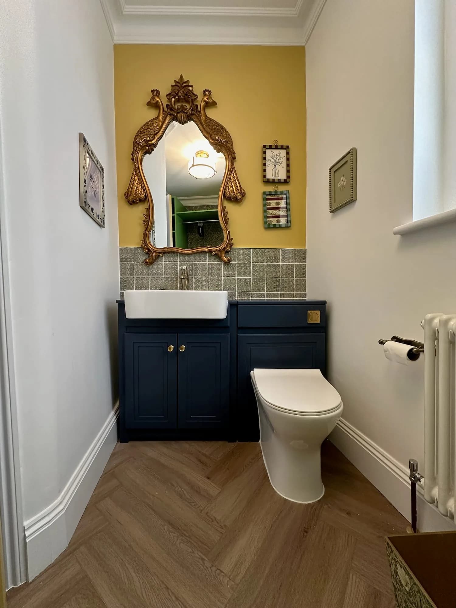 Earls Court I: cloakroom with a gilt mirror, ochre walls and a navy vanity unit