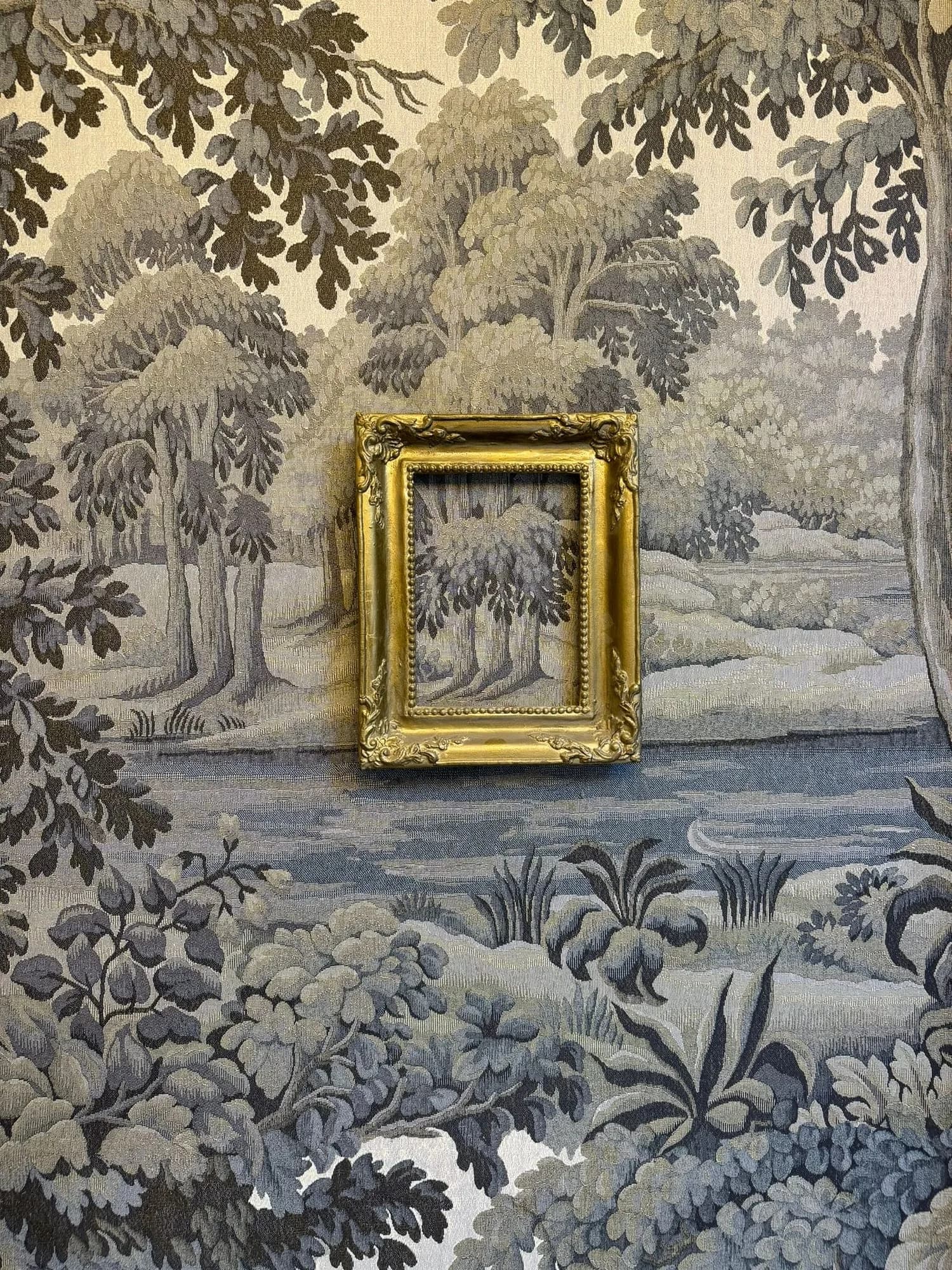 Earls Court III: gilt picture frame hung on a woodland mural wallcovering