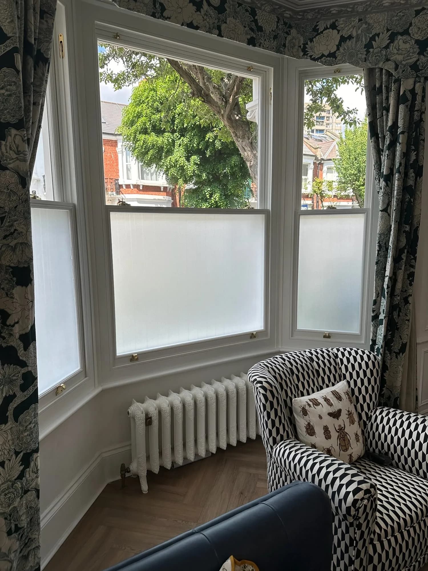 Earls Court II: bay window with a cast-iron radiator and patterned curtains