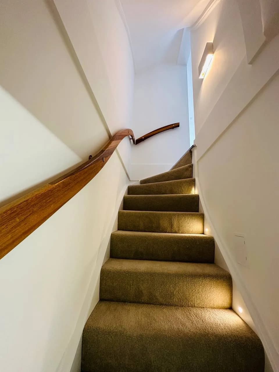 High Street Kensington: staircase with lit treads and a curved timber handrail
