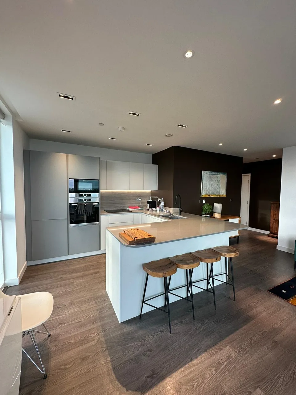 Finsbury Park: open-plan kitchen with a white island, breakfast stools and integrated ovens