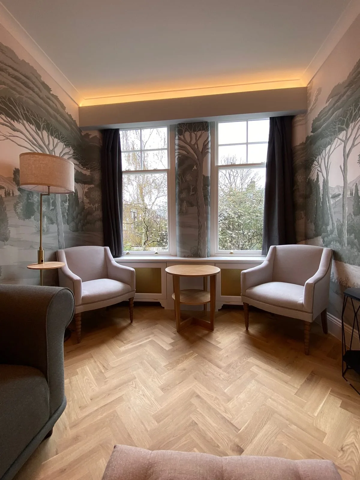 Sitting room with hand-painted mural walls, herringbone parquet and a bay window