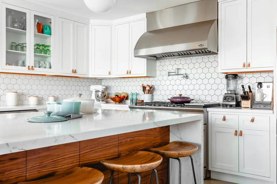 Kitchen island with a marble worktop, walnut panelling and hexagonal wall tiles