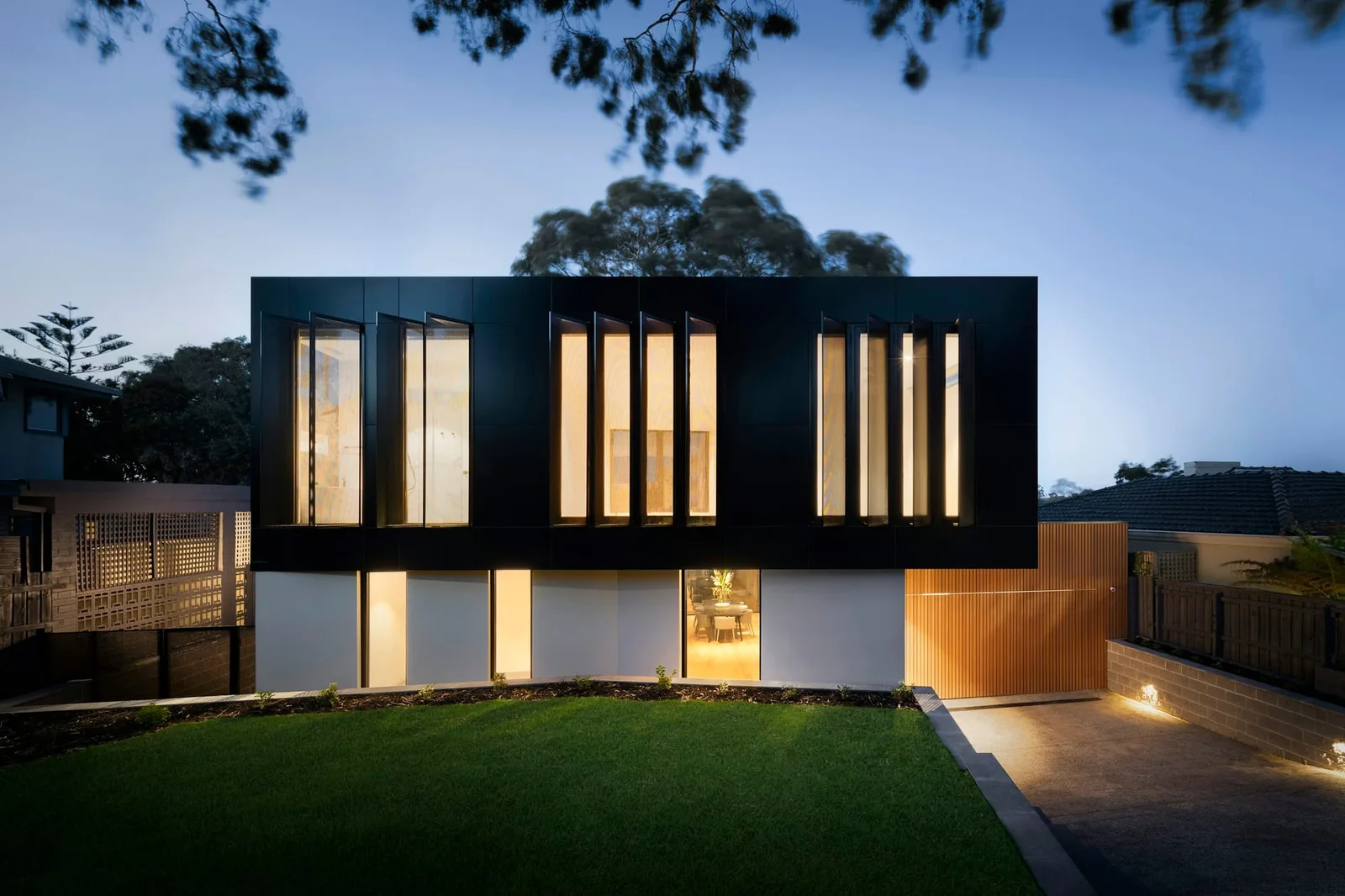 House at dusk with warm lighting glowing through tall slot windows