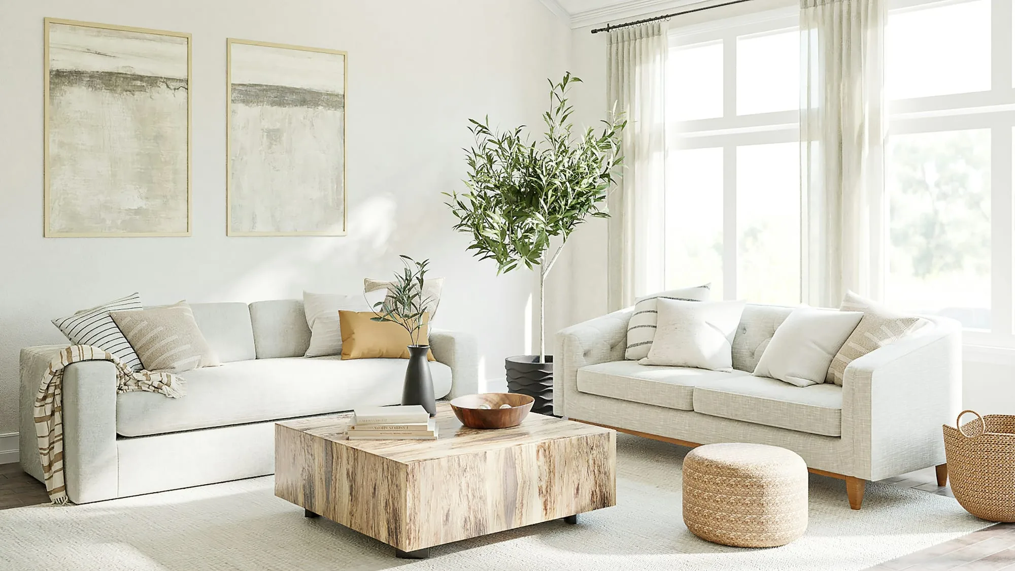 Living room styled in cream and stone with an olive tree and a low travertine table