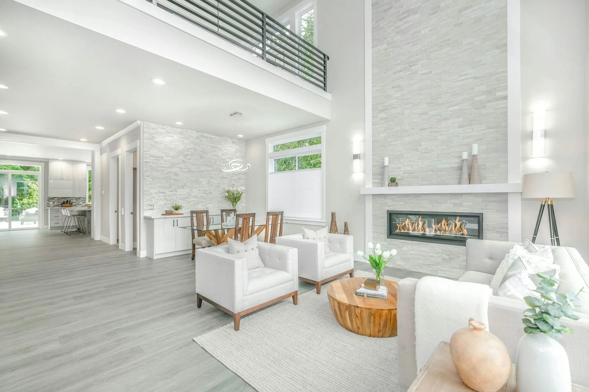Double-height living room with a mezzanine walkway and a stone fireplace